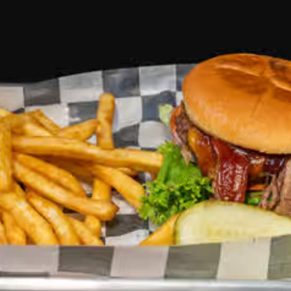 A BBQ burger with fries and a pickle spear in a checkered basket at Endzone Bar & Grill.