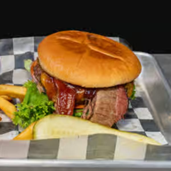 Endzone Bar & Grill's BBQ brisket sandwich with fries and a pickle on a checkered paper.