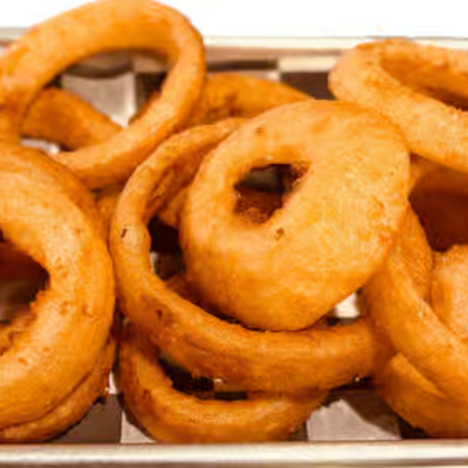 Golden-brown, crispy onion rings piled high in a metal basket with a checkered paper liner.