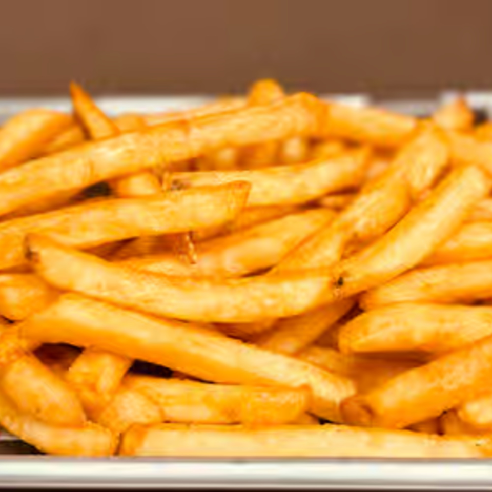 Close-up of golden-brown french fries, a classic bar-and-grill side dish, in a metal tray.