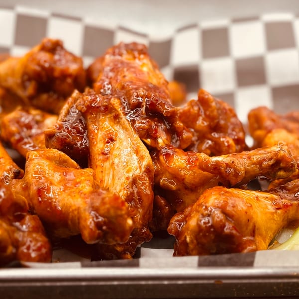 Close-up of Endzone Bar & Grill's saucy chicken wings in a checkered paper-lined basket.