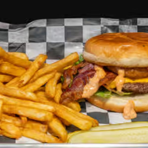 Endzone Bar & Grill's bacon cheeseburger with fries and a pickle spear on checkered paper.
